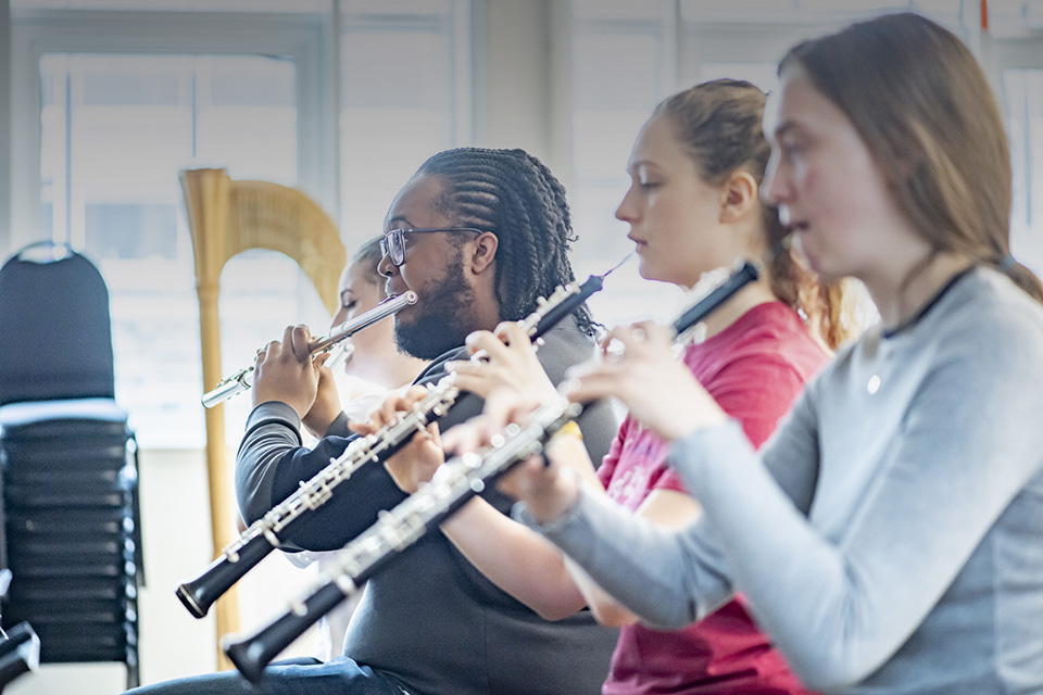 A group of students performing on woodwind instruments, an oboe and flute.